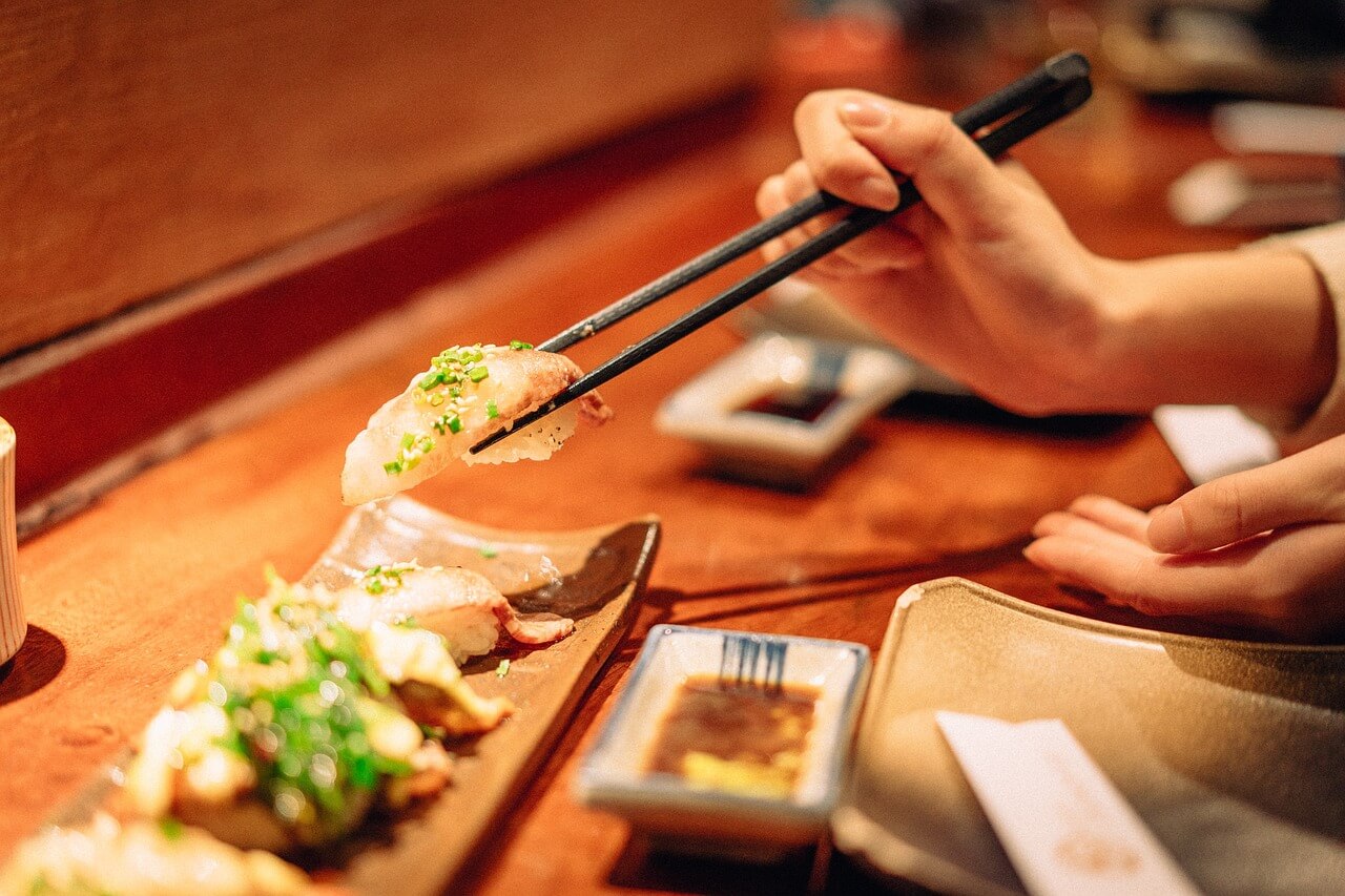 A person picking up sushi with chopsticks