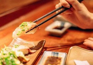 A person picking up sushi with chopsticks
