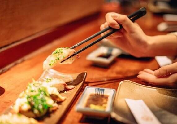 A person picking up sushi with chopsticks